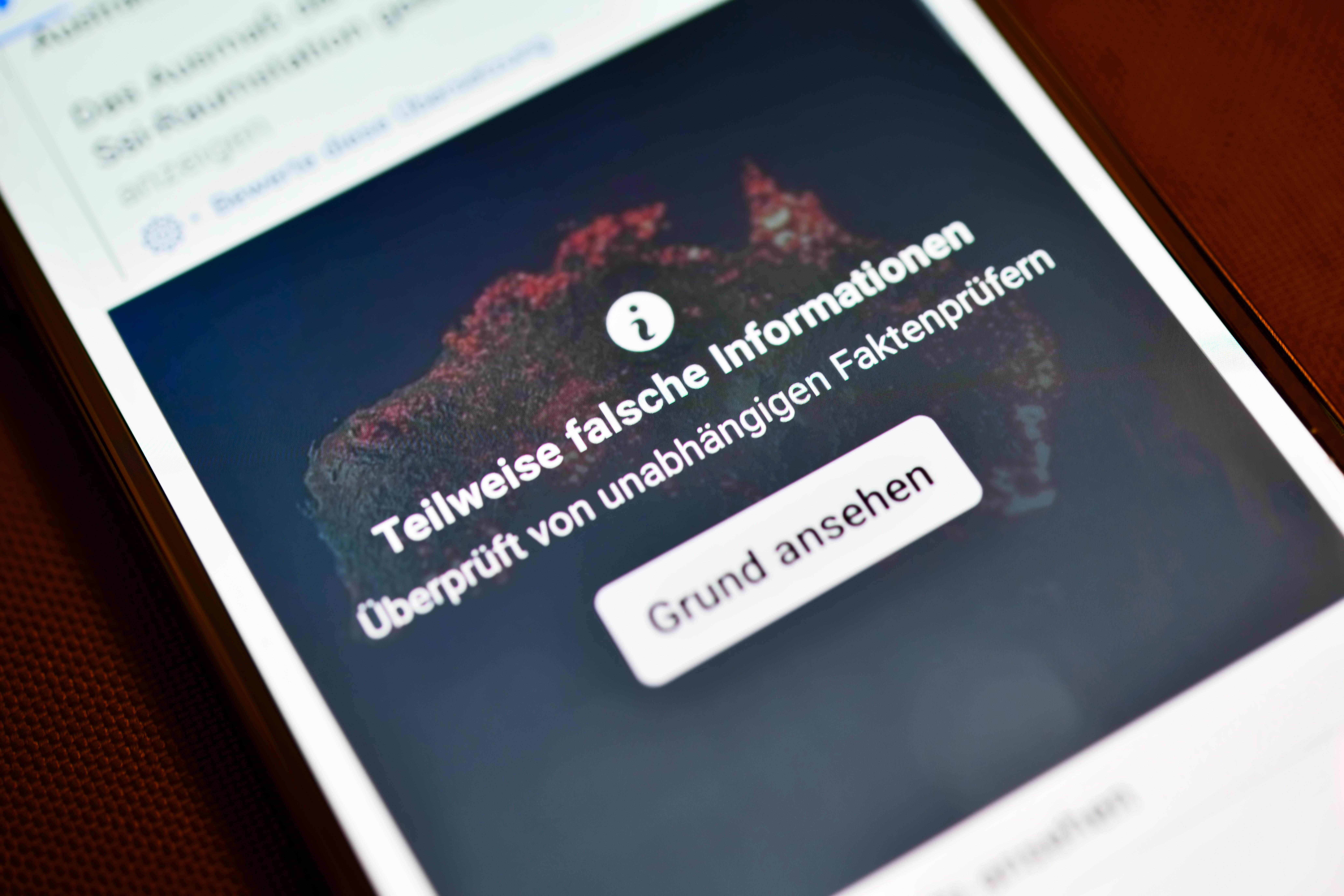 Ein Smartphone mit aufgedeckter Falschinformation in einem sozialen Netzwerk (Symbolbild)