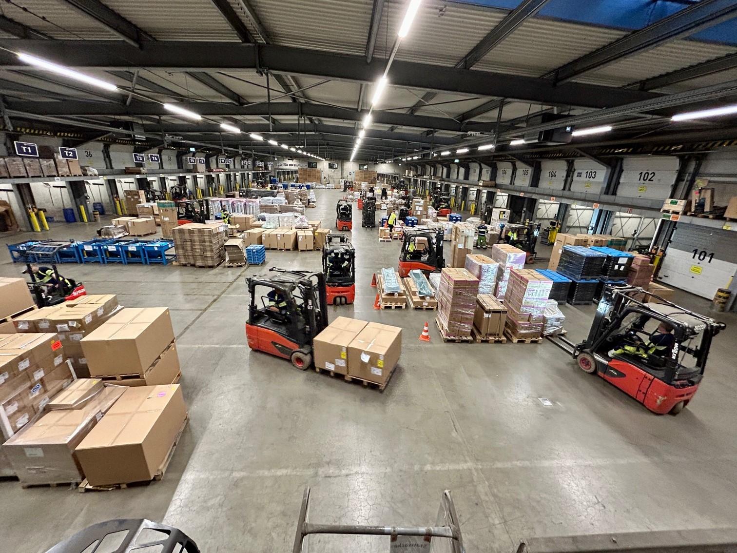 Gabelstapler fahren mit Paketen durch eine große Logistikhalle.