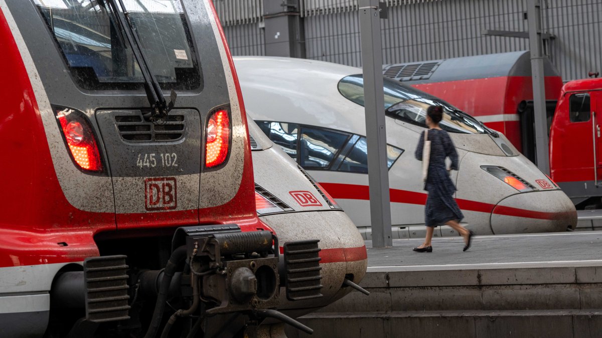 Zugreisende gehen an Zügen der Deutschen Bahn im Münchner Hauptbahnhof vorbei. 