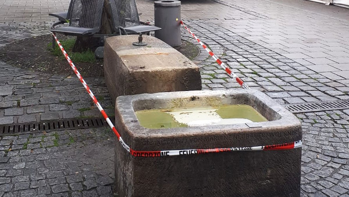 Die Reste des Ida-Schumacher-Brunnens am Münchner Viktualienmarkt sind mit Absperrband der Feuerwehr umwickelt
