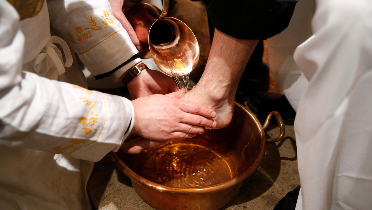 Ein Priester wäscht am Gründonnerstag im Gottesdienst Menschen die Füße.