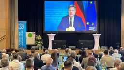 In einem Saal sitzen viele Männer und schauen auf Bundeswirtschaftsminister Robert Habeck, der per Video zugeschaltet  ist.  | Bild:BR/Christoph Röder 