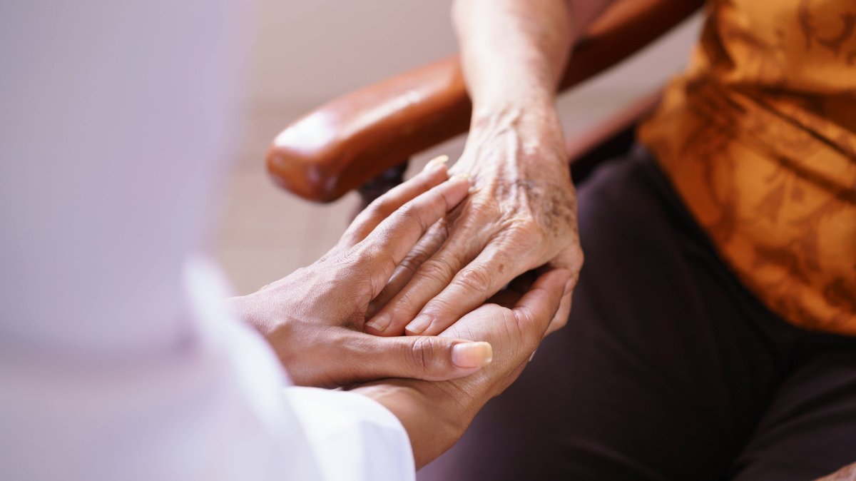 Symbolbild: Eine Frau hält einer Seniorin im Altenpflegeheim die Hand