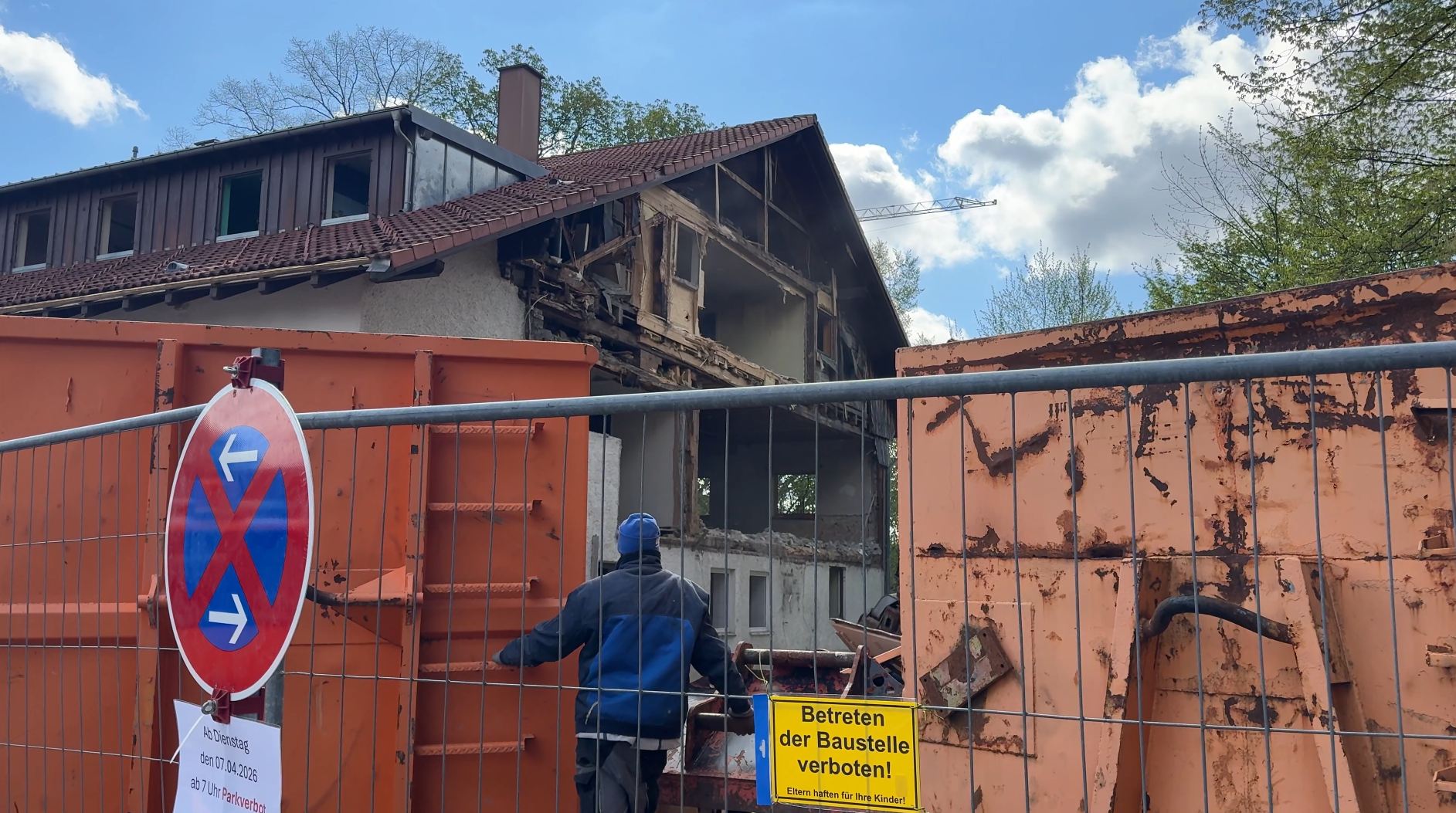 Ein Arbeiter steht hinter einem Bauzaun und blickt auf die bereits teilweise abgebrochene Fassade des Gasthauses zum Löwen in Lauben.