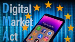 Ein Smartphone mit verschiedenen Apps, ganz oben links WhatsApp – im Hintergrund eine EU-Flagge mit dem Schriftzug "Digital Market Act" | Bild:picture alliance / NurPhoto | Jonathan Raa