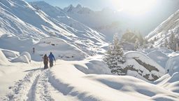 Zwei Menschen laufen durch hohen Schnee in den Schweizer Bergen | Bild:Stefan Schlumpf photography