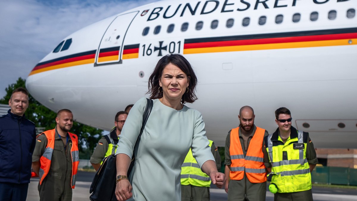 Annalena Baerbock (Bündnis 90/Die Grünen), Außenministerin, geht nach der Landung über den Flughafen. Im Hintergrund: ein Regierungsflieger.