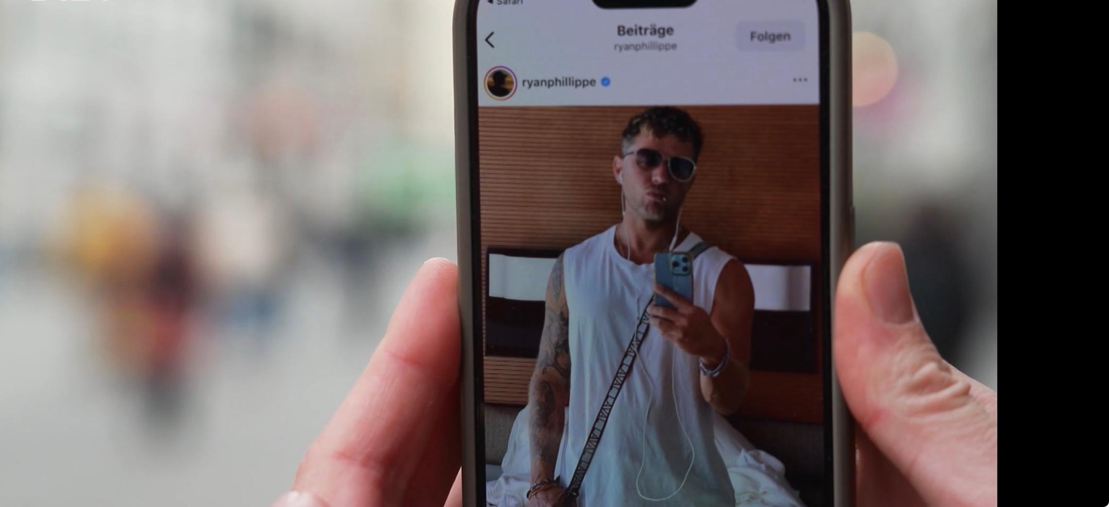 Hand hält Smartphone, auf der  Hollywood-Schauspieler Ryan Philippe mit Zahnstocher zu sehen ist