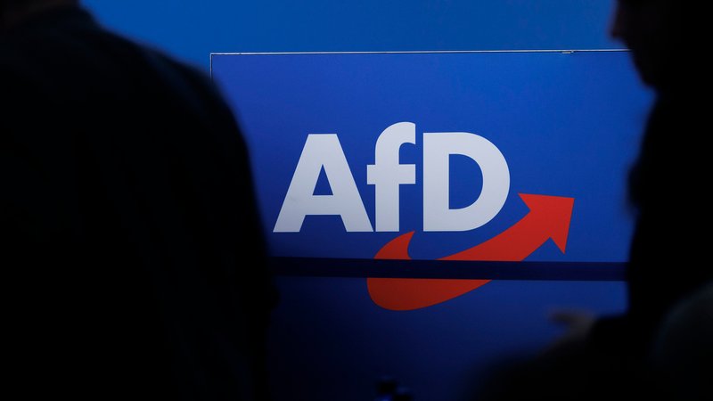 ARCHIV - 28.07.2023, Sachsen-Anhalt, Magdeburg: Delegierte gehen vor dem Parteilogo bei dem AfD-Bundesparteitag in Magdeburg. | Bild: dpa-Bildfunk/Carsten Koall ARCHIV - 28.07.2023, Sachsen-Anhalt, Magdeburg: Delegierte gehen vor dem Parteilogo bei dem AfD-Bundesparteitag in Magdeburg.