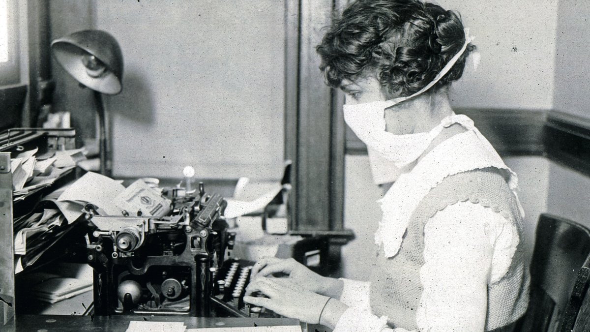  Schreibkraft im Jahr 1918 mit Mundschutz an der Schreibmaschine