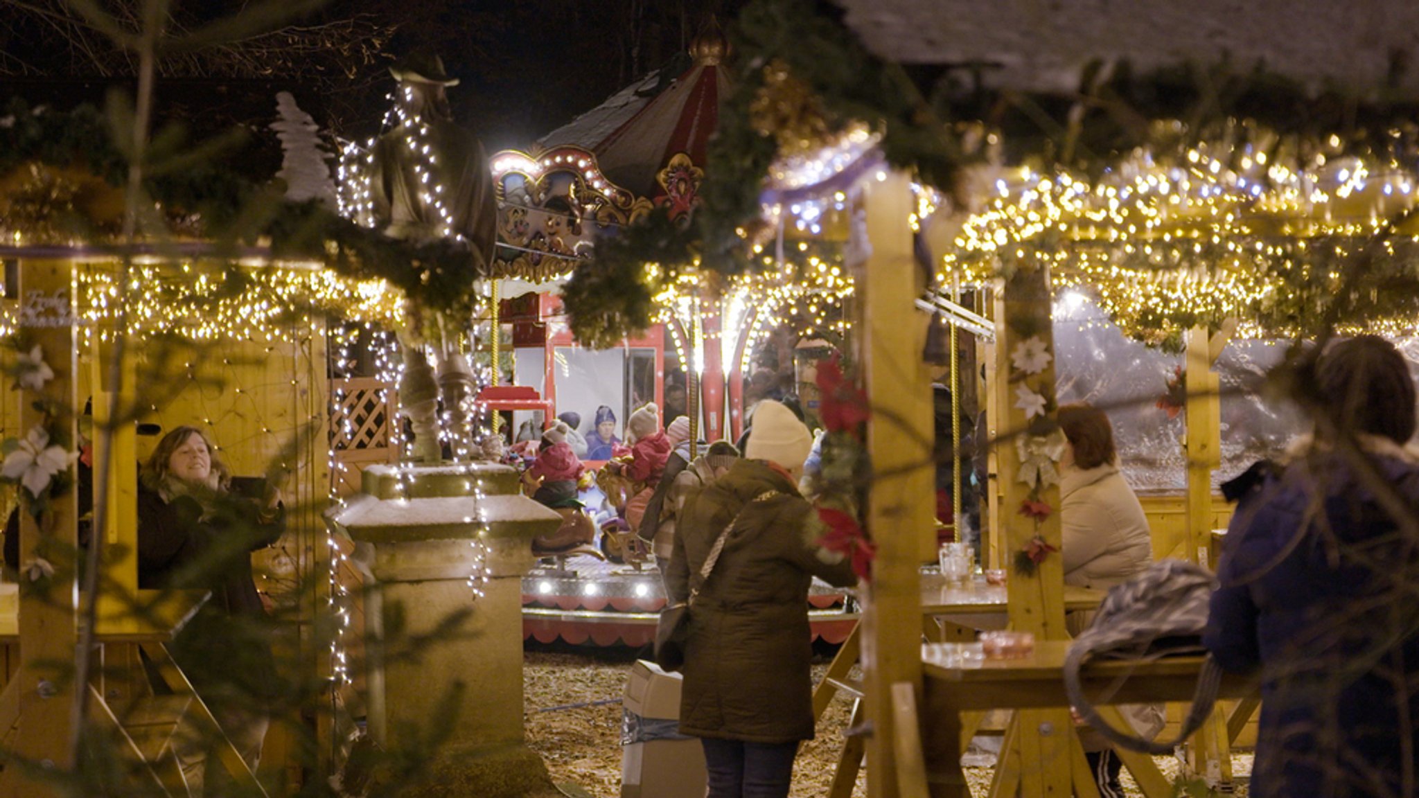 Buden und ein Kinderkarussell auf einem Weihnachtsmarkt