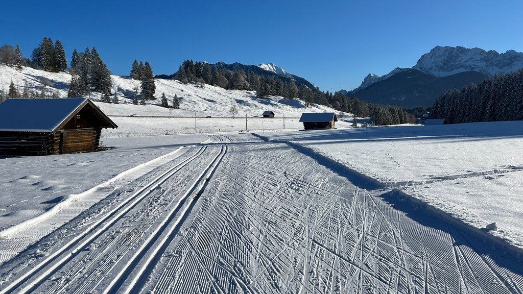 Langlauf-Loipen und Skating-Spur vor blauem Himmel, im Hintergrund schneebedeckte Berge  - ein Wintertraum vor einer Woche  in Kaltenbrunn südlich von Garmisch-Partenkirchen