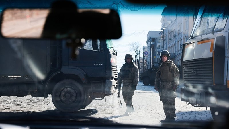 In Kiew stehen zwei Soldaten zwischen zwei Lastwagen, die die Straße blockieren (Symbolbild)