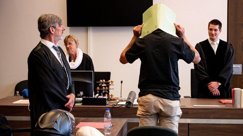 Der Angeklagte verbirgt seinen Kopf hinter einer Aktenmappe vor Gericht in Berlin.