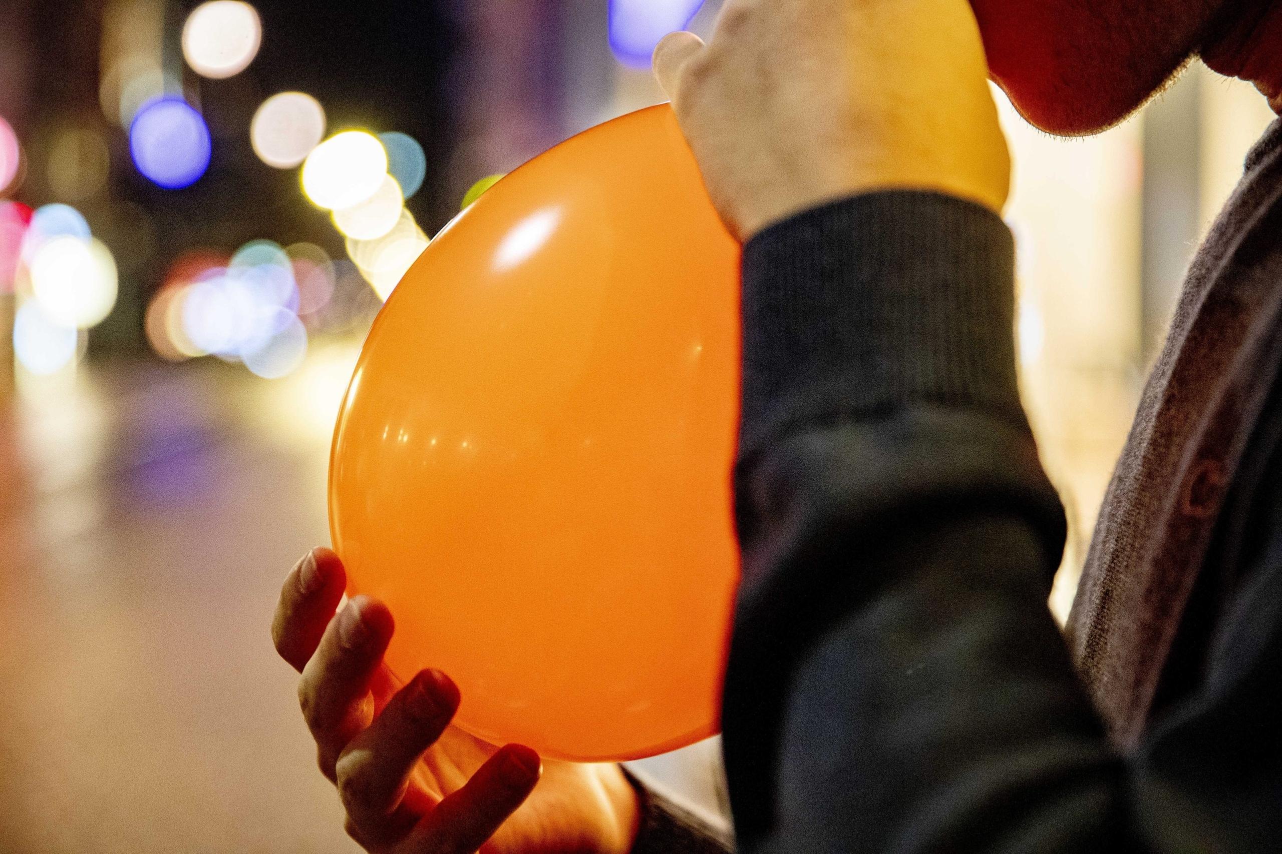 Junger Mann inhaliert Lachgas aus einem Luftballon.