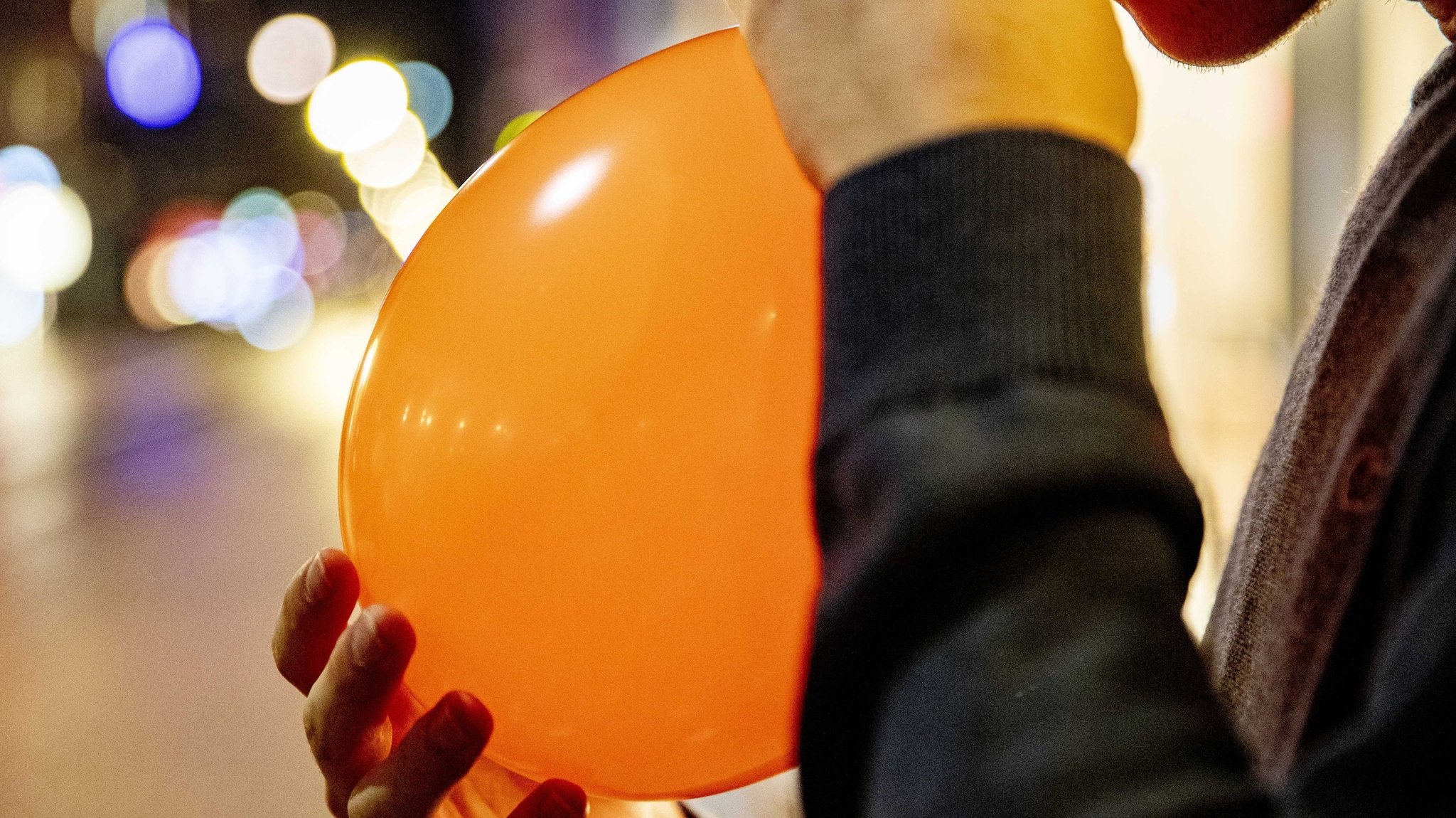 Junger Mann inhaliert Lachgas aus einem Luftballon.