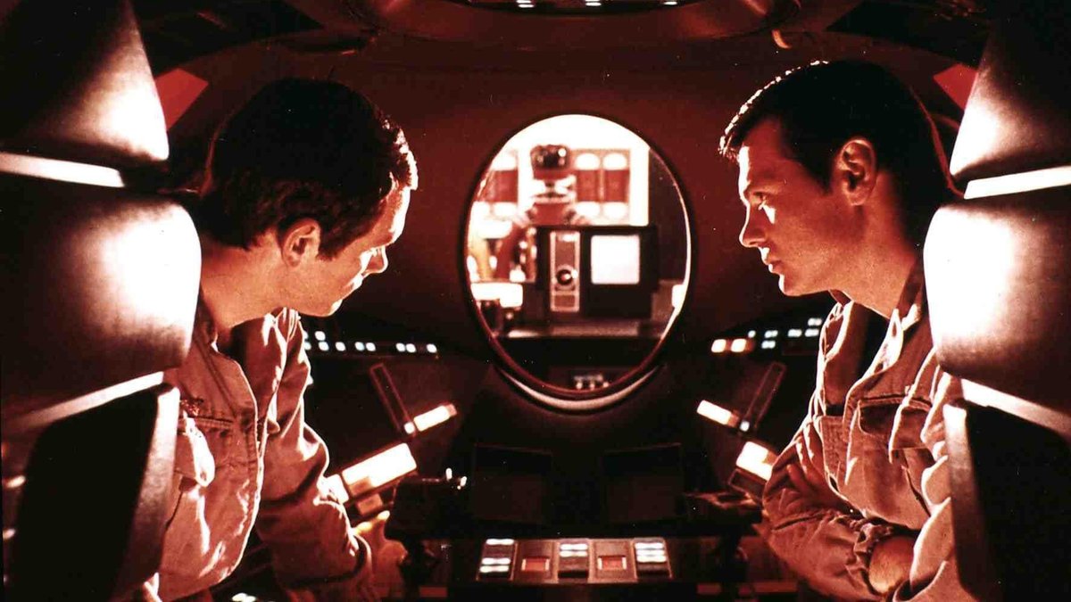 Die Astronauten David (Keir Dullea, l) und Frank (Gary Lockwood, r) unterhalten sich, im roten LIcht des roten "Auges" des Computers HAL 9000. Filmszene aus "2001: A Space Odyssey"