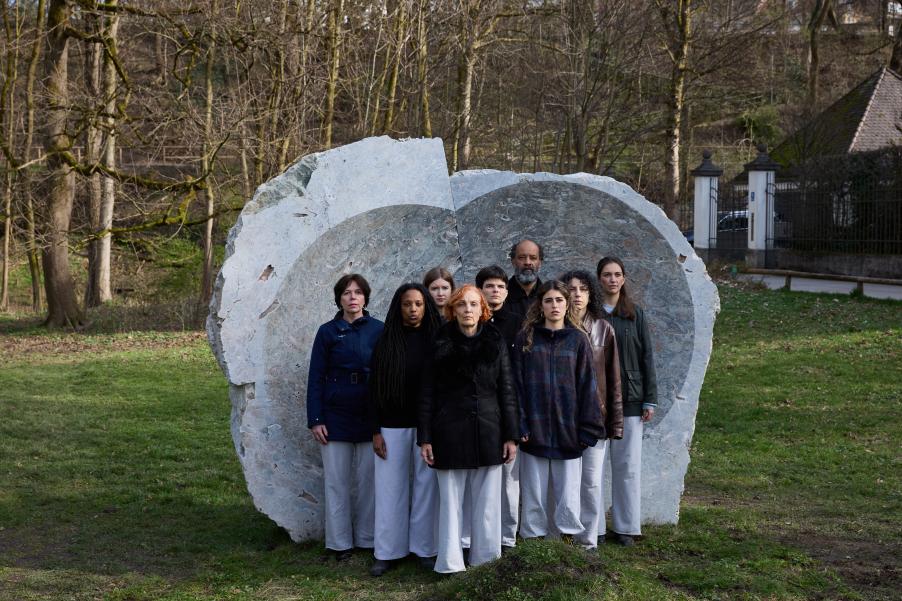 Männer und Frauen stehen vor einer Skulptur.