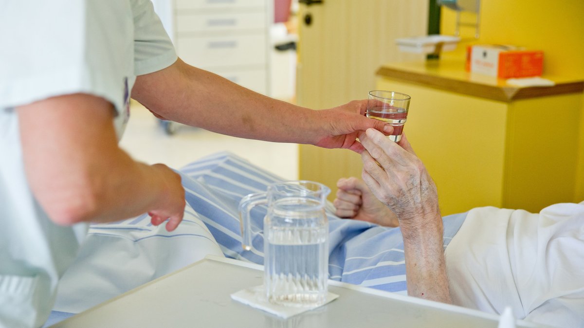 Ein Pfleger hilft einer Seniorin