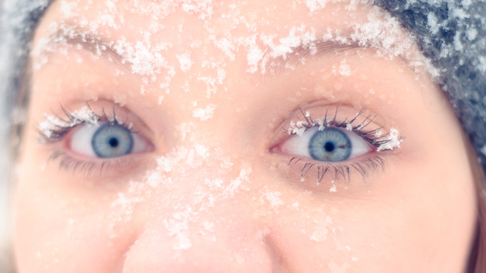 Gesicht mit blauen Augen und Schneeflocken auf der Haut