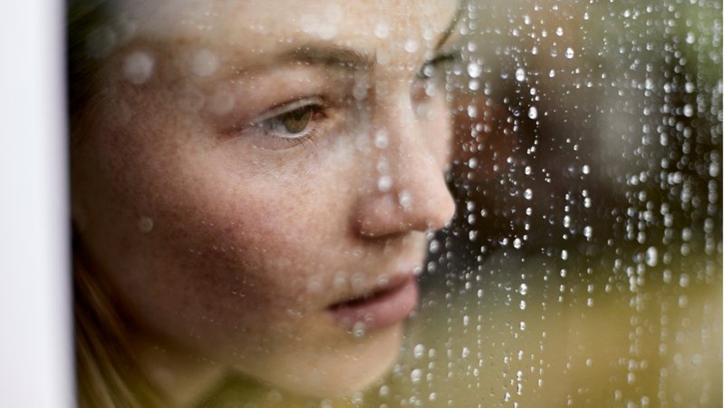 Eine junge Frau sieht aus einem verregneten Fenster hinaus. Die Zahl einsamer Menschen in Deutschland steigt - besonders unter Jugendlichen und jungen Erwachsenen. Wie äußert sich Einsamkeit und was könnt ihr dagegen tun?