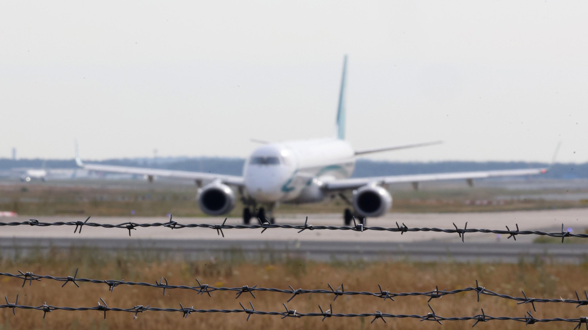 Ein Flugzeug steht auf dem Rollfeld des Flughafens. Das Gelände ist mit Stacheldraht gesichert.