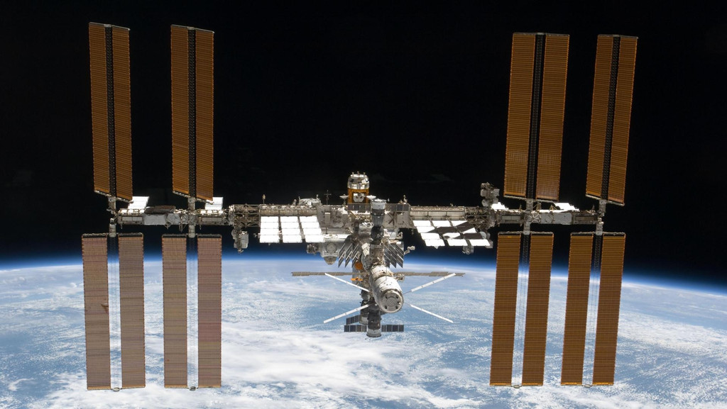 Die Aufnahme zeigt die Internationale Raumstation ISS in einer niedrigen Erdumlaufbahn. Im Hintergrund befindet sich die Erde. 
