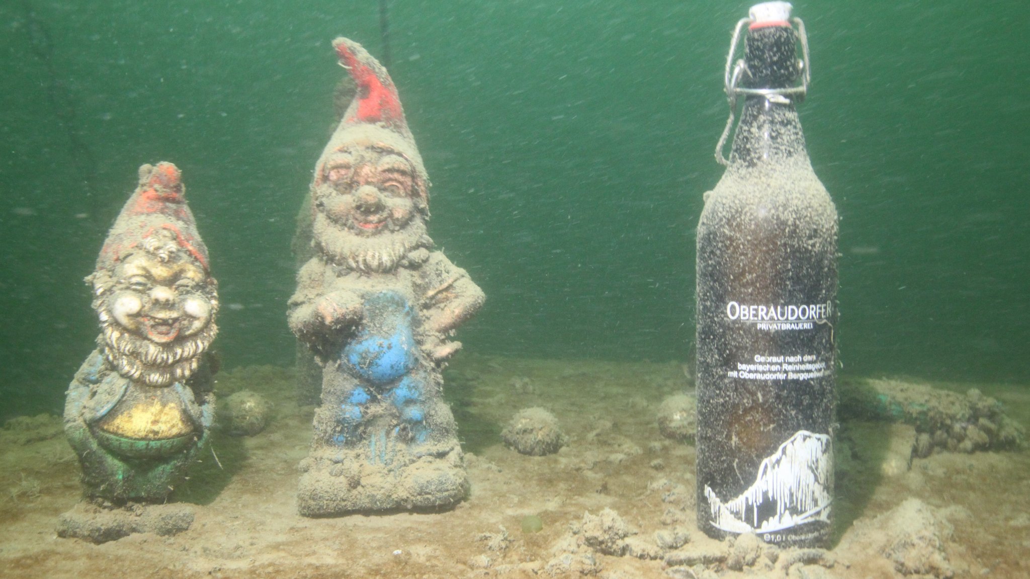 Gartenzwerge mit Bierflasche auf dem Seegrund