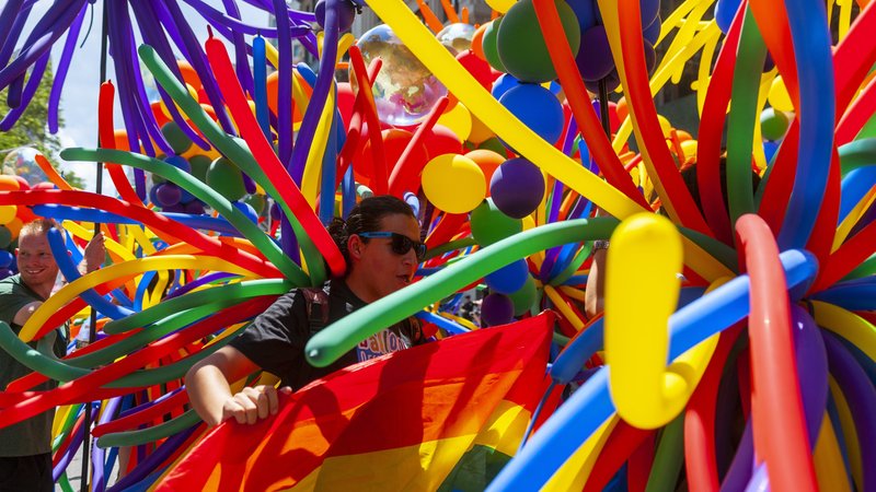 Viele bunte Luftballons bei der Gay Pride Parade in New York. Dazwischen eine Person mit dunkler Sonnenbrille