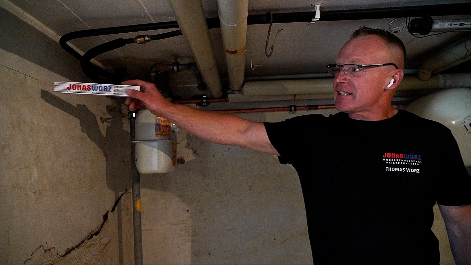 Offingens Bürgermeister Wörz steht im Keller seines Elternhauses und zeigt auf die Stelle, bis zu der das Hochwasser den Keller geflutet hatte. 