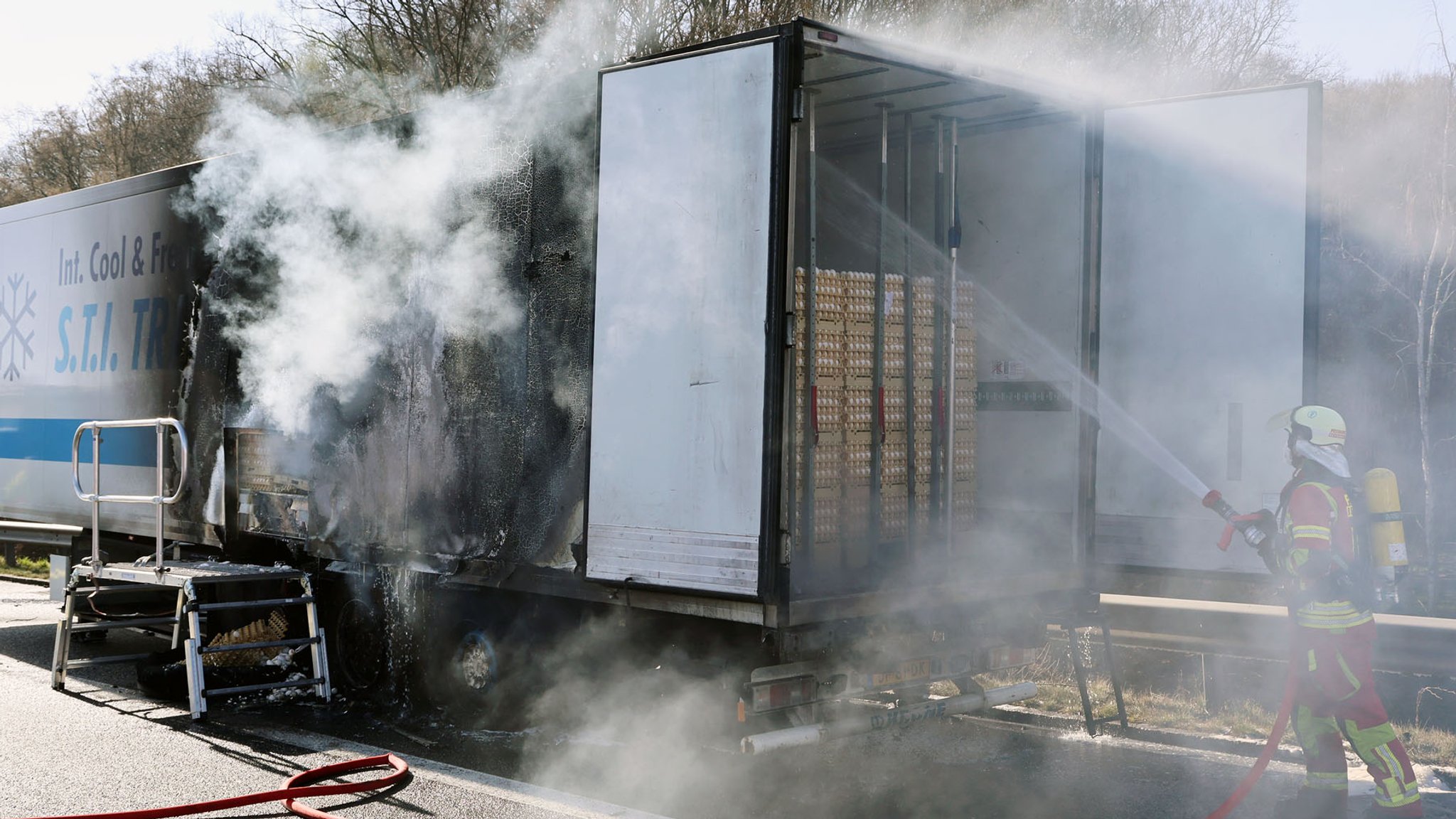 Feuerwehrleute löschen auf der A3 einen mit 300.000 Eiern beladenen Kühl-Auflieger.