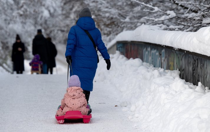 04.12.2023, Bayern, München: Eine Frau zieht ein Kind auf einem Schlitten über einen Gehweg. Schnee und Eis sorgen auf den Straßen im Süden Bayerns weiterhin für Chaos. Foto: Sven Hoppe/dpa +++ dpa-Bildfunk +++