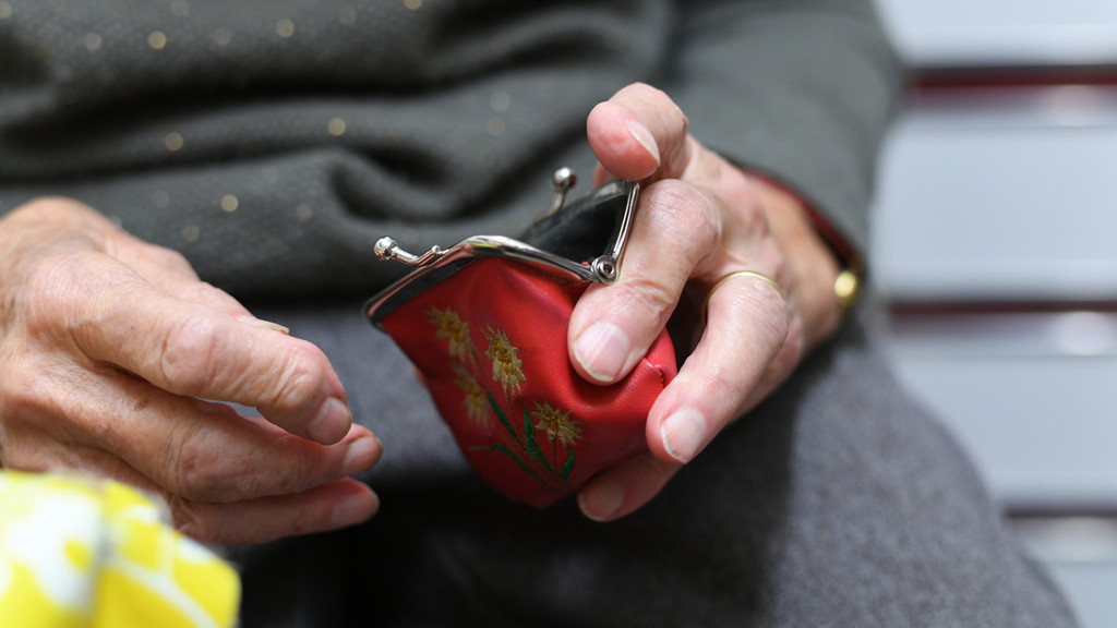 Eine Rentnerin hält ihren geöffneten Geldbeutel in ihrer Hand.