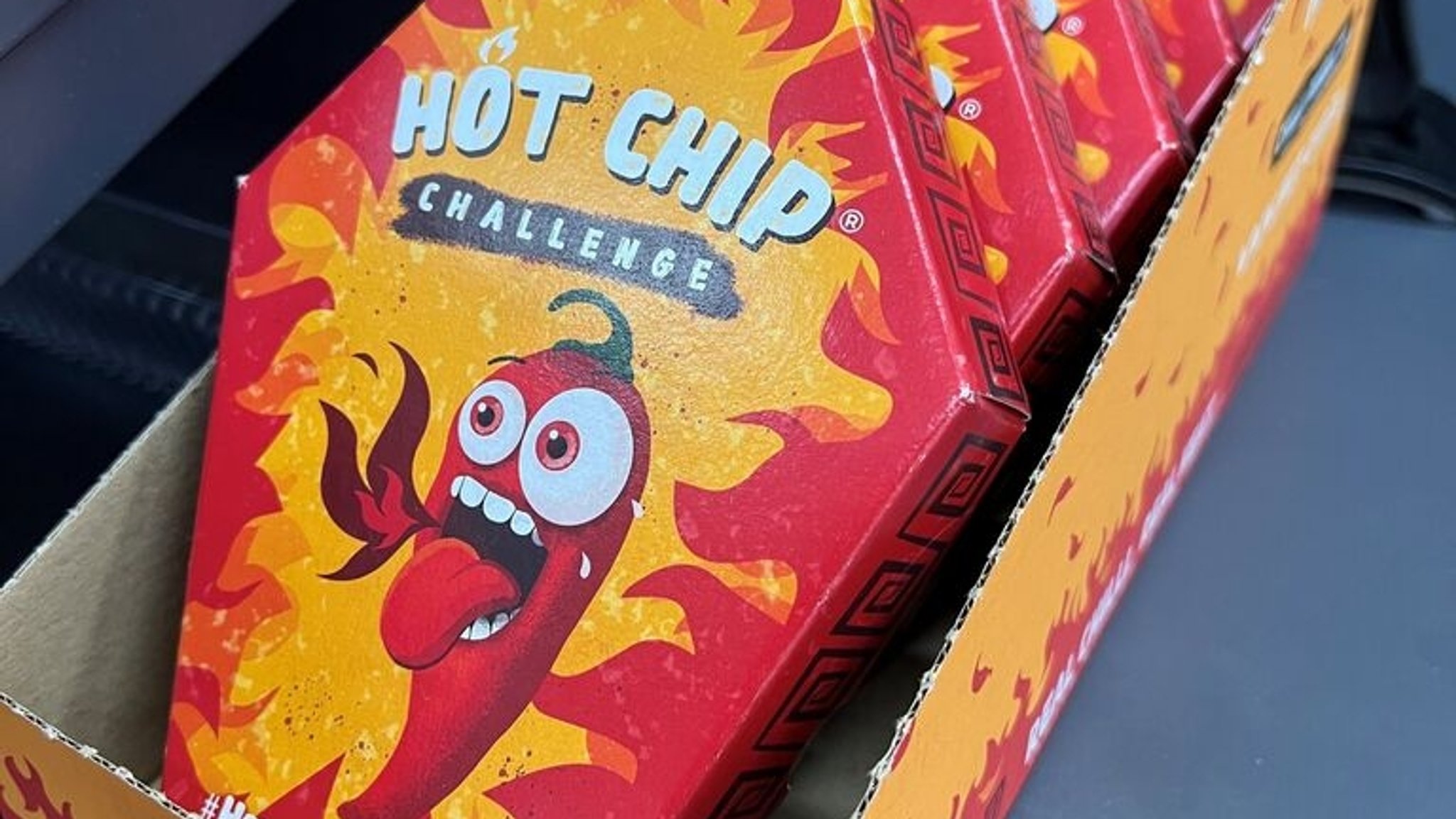 ARCHIV - 22.09.2023, Berlin: Mehrere Packungen für die so genannte "Hot Chip Challenge" liegen neben der Kasse eines Kiosks. Die Verpackung der «Hot Chip Challenge» in der Form eines Sarges enthält einen einzigen extrem scharfen Tortillachip - sowie Latexhandschuhe zum Anfassen. Gewürzt sind die Tortillachips mit der schärfsten Chili-Sorte der Welt. Vor allem im Internet haben sich die «Hot Chips» wegen ihrer Schärfe per Videos in den sozialen Medien ausbreitet. (zu dpa«Hot Chip Challenge»: Hersteller stoppt Export nach Deutschland) Foto: Doreen Garud/dpa +++ dpa-Bildfunk +++