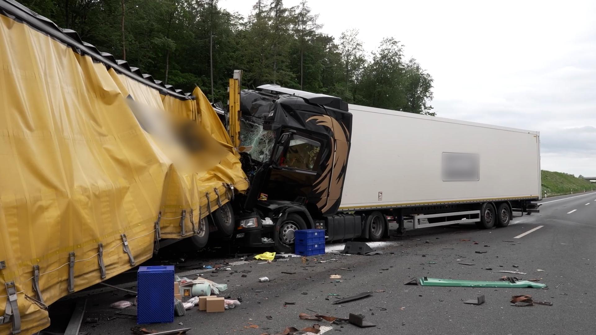 Unfall mit zusammengestoßenen LKW auf der A3. Trümmer und blaue Boxen liegen auf der Fahrbahn.