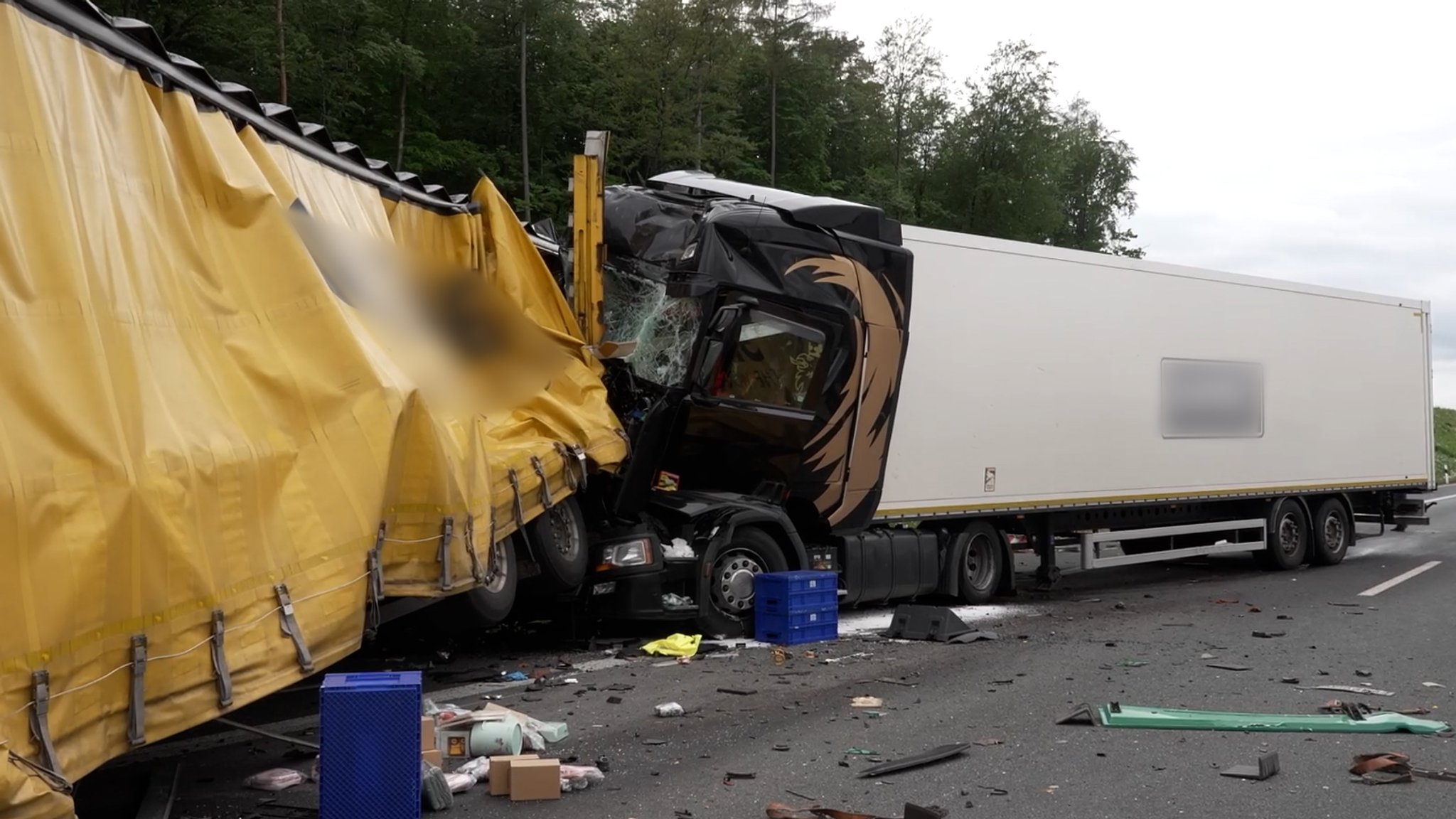 Unfall mit zusammengestoßenen LKW auf der A3. Trümmer und blaue Boxen liegen auf der Fahrbahn.