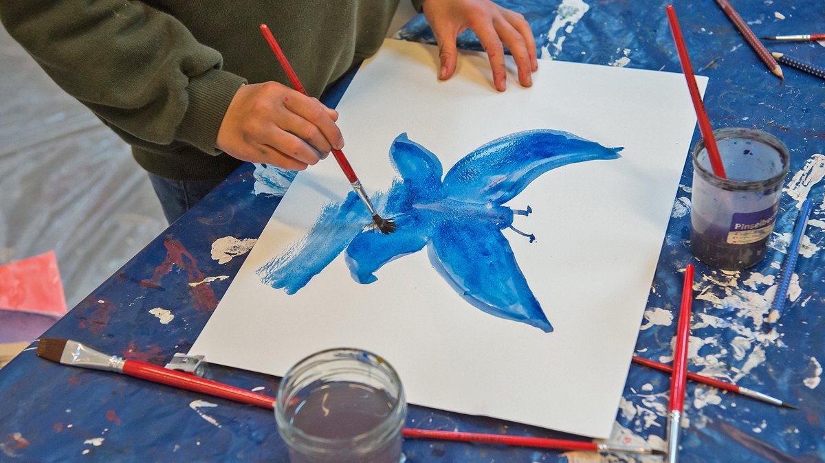 Kind malt einen blauen Schmetterling