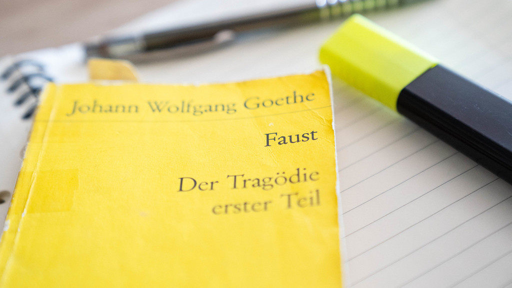 Goethes "Faust" liegt neben einem Textmarker und Kugelschreiber auf einem Notizbuch.