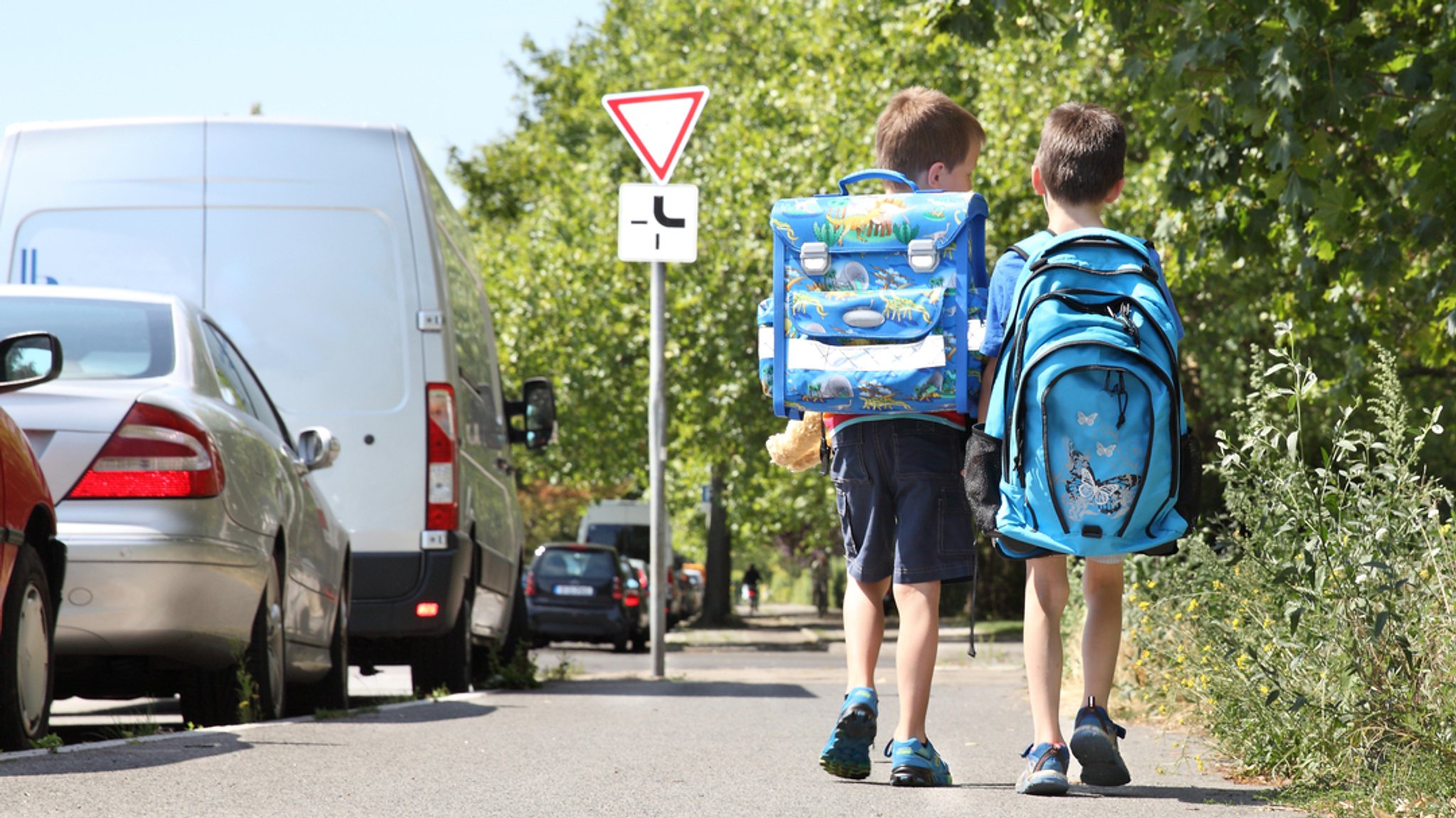 Zu sehen sind zwei junge Schüler auf einem Gehweg.