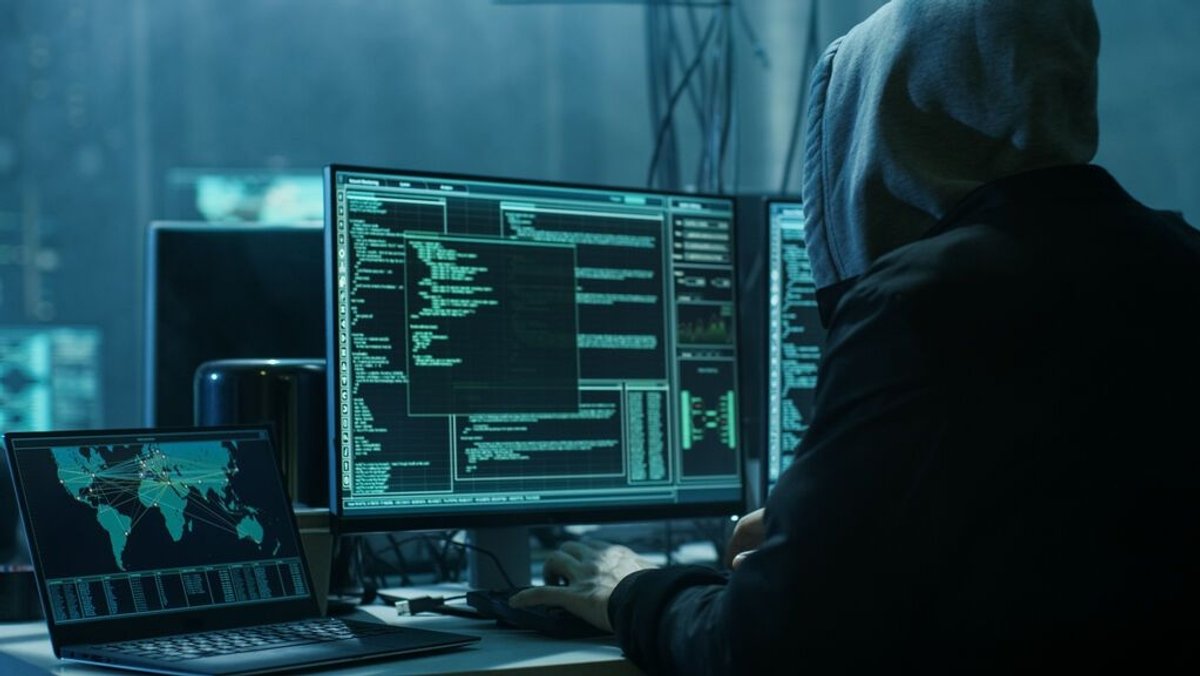 Ein Mann sitzt vor einem Computer und hackt.
