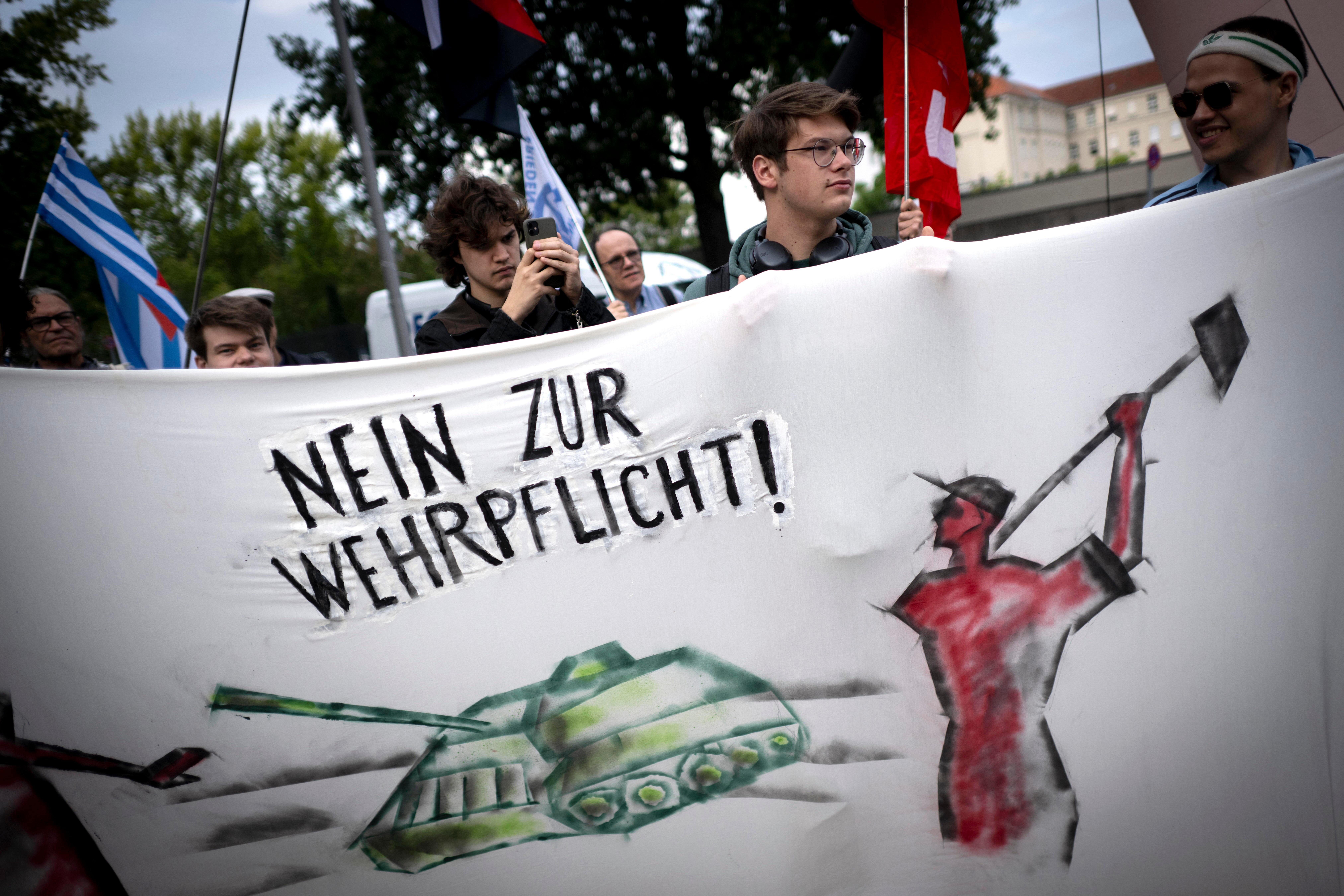 Ein junger Mann hält ein Banner. Darauf steht "Nein zur Wehrpflicht".