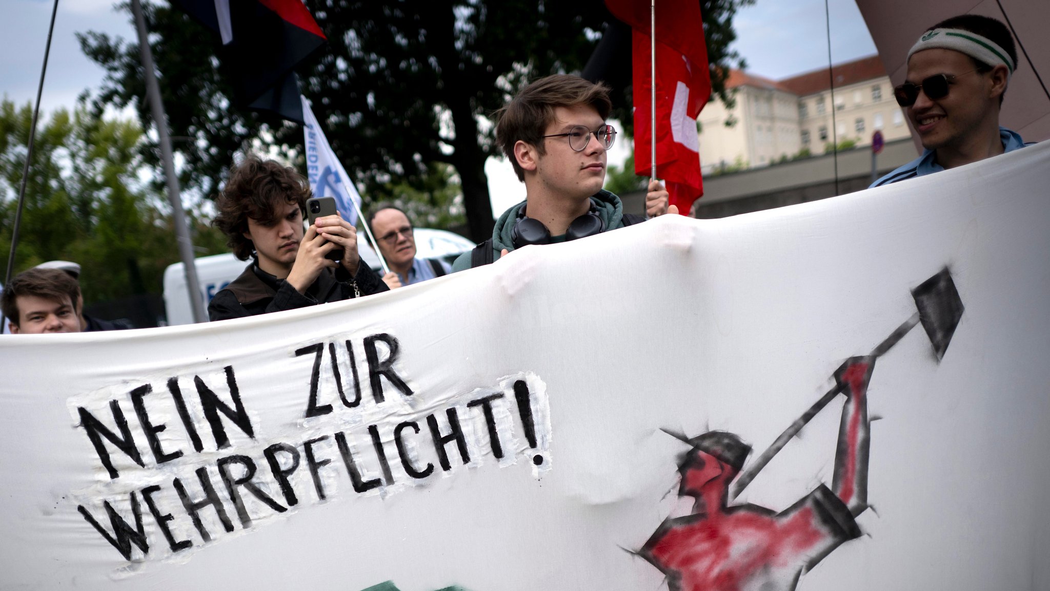 Ein junger Mann hält ein Banner. Darauf steht "Nein zur Wehrpflicht".