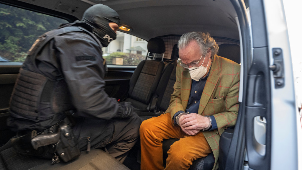 Bei einer Razzia gegen sogenannte "Reichsbürger" sitzt ein vermummter Polizist, nach der Durchsuchung eines Hauses, mit dem festgenommenen Heinrich XIII Prinz Reuß (r) in einem Polizeifahrzeug.