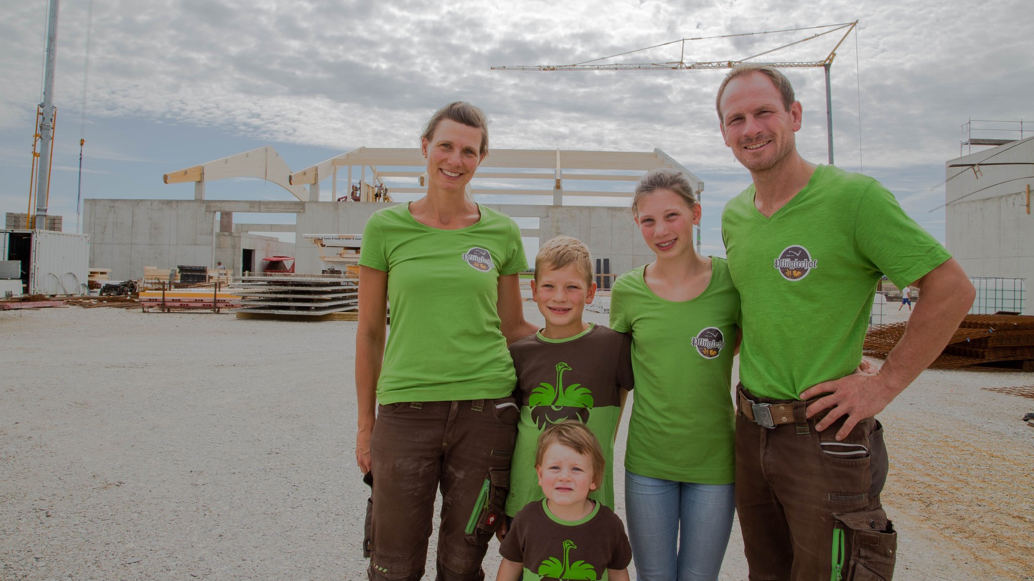 Familie Pflügler steht auf der Baustelle für ihren neuen Pflüglerhof