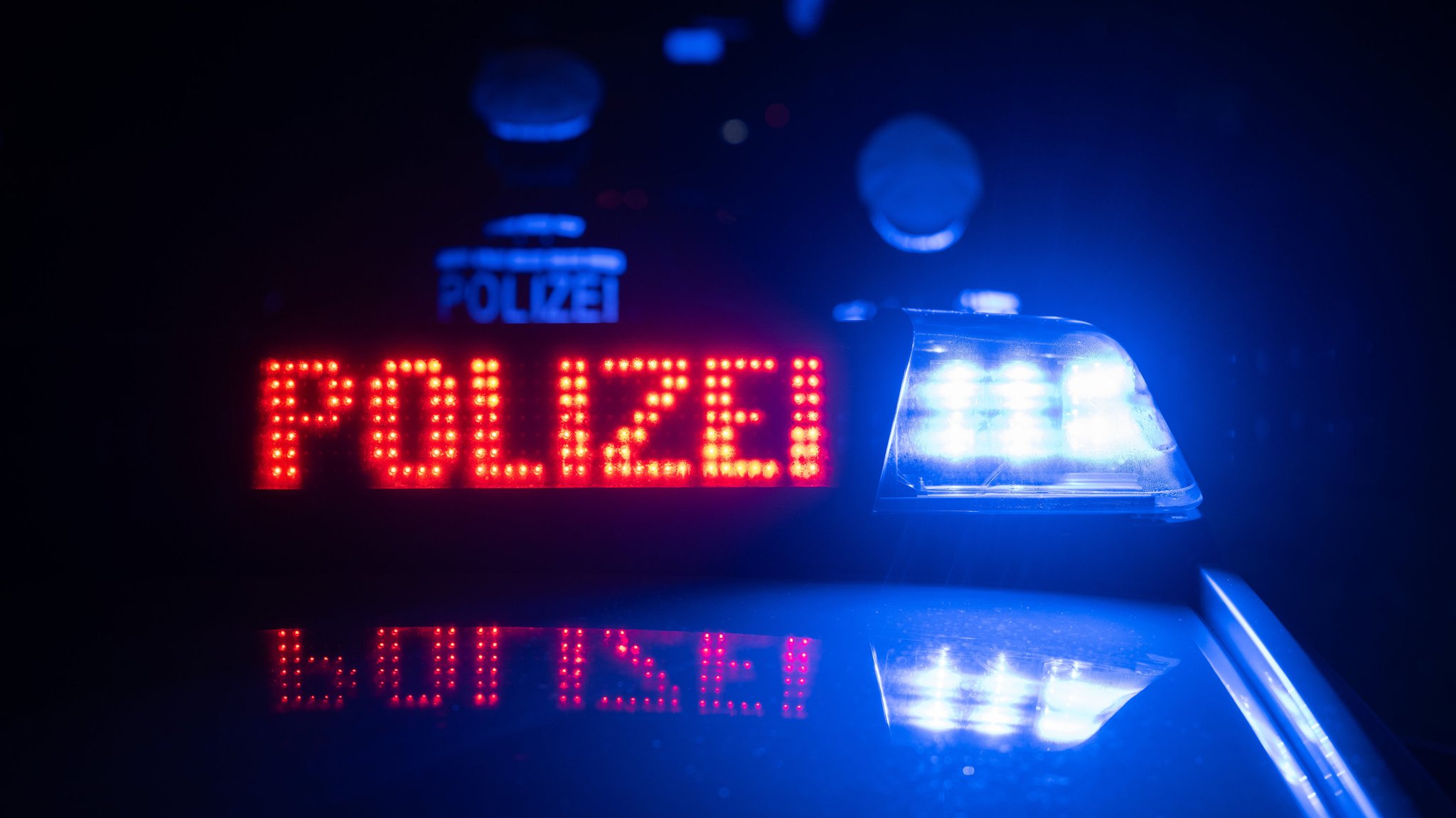 Zwei Polizisten stehen im Dunkeln vor einem Polizeiauto, auf dem ein Blaulicht und die Aufschrift "Polizei" blinkt. | Bild: dpa-Bildfunk/Marijan Murat Zwei Polizisten stehen im Dunkeln vor einem Polizeiauto, auf dem ein Blaulicht und die Aufschrift "Polizei" blinkt.