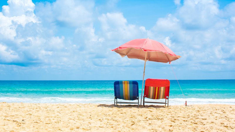 Zwei liegen und ein Sonnenschirm stehen an einem Strand mit blauem Meer | Bild: stock.adobe.com/satit Zwei liegen und ein Sonnenschirm stehen an einem Strand mit blauem Meer