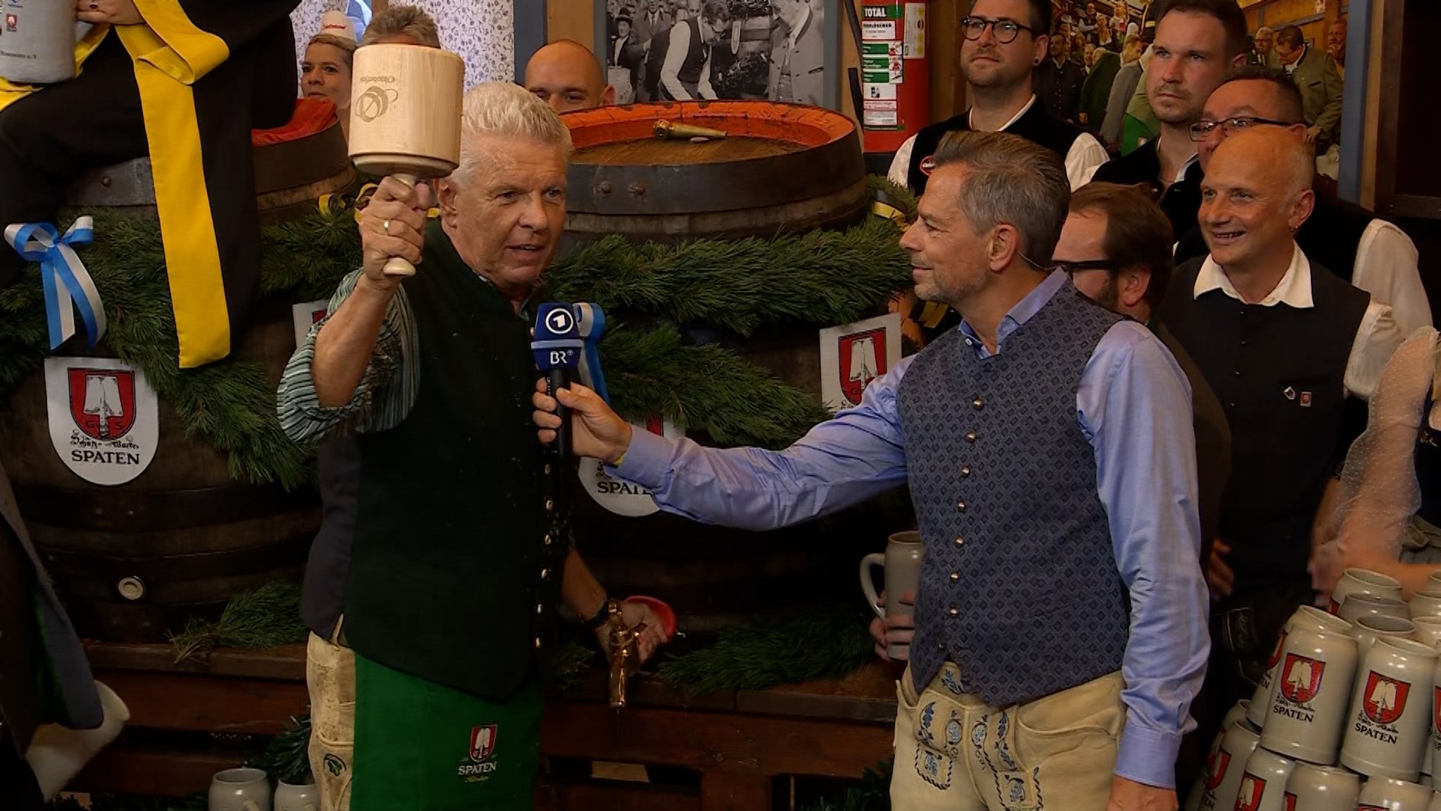 Oberbürgermeister Dieter Reiter am ersten Bierfass des 190. Oktoberfestes mit dem Anzapf-Schlegel in der Hand, BR-Moderator Michael Sporer hält ihm das Mikrofon hin.