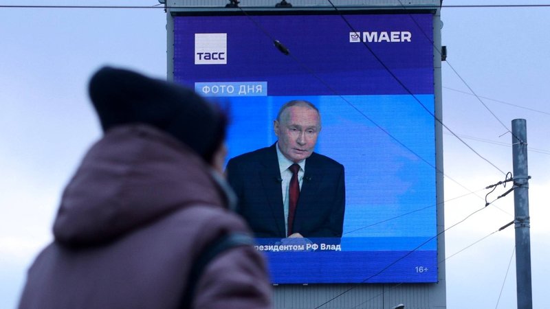 Passantin geht an einem Bildschirm vorbei, auf dem eine Putin-Pressekonferenz übertragen wird | Bild: Maria Semenova/Picture Alliance Passantin geht an einem Bildschirm vorbei, auf dem eine Putin-Pressekonferenz übertragen wird