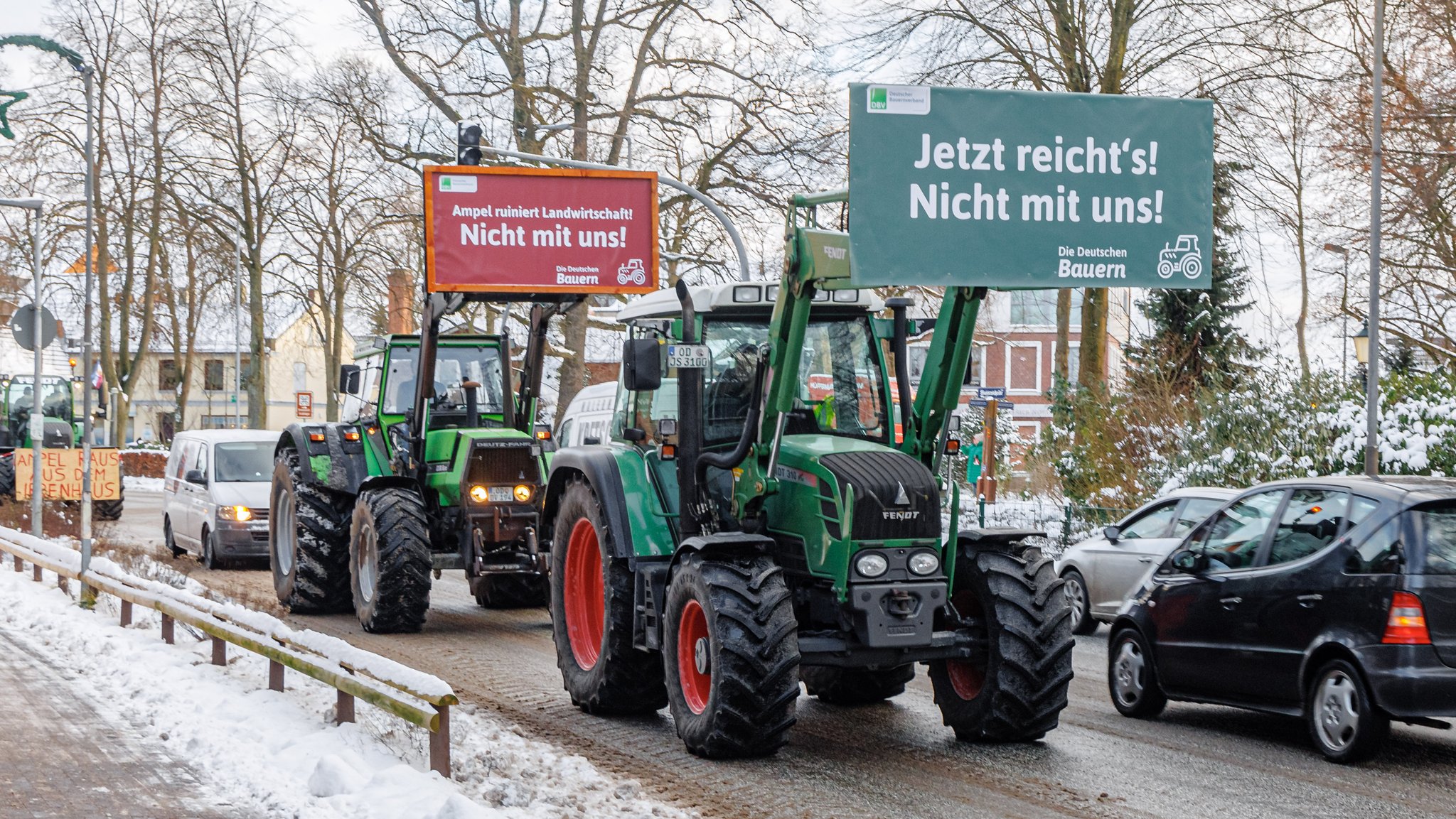 Ein Protestzug von Bauern fährt mit Plakaten eine Straße entlang.