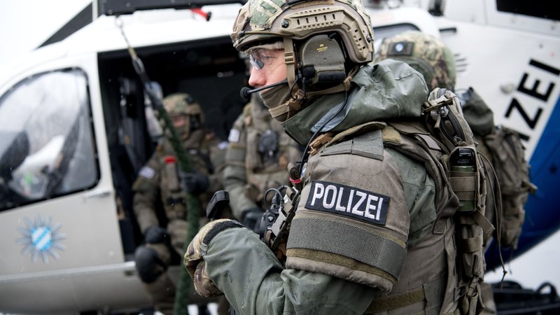 Polizisten des Spezialeinsatzkommando Südbayern vor einem Hubschrauber 